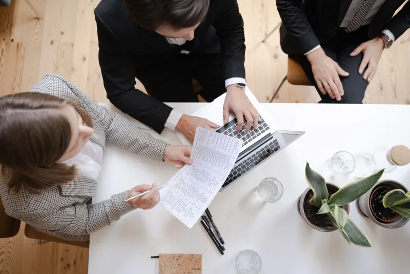An overhead view of a business meeting with a laptop and documents.