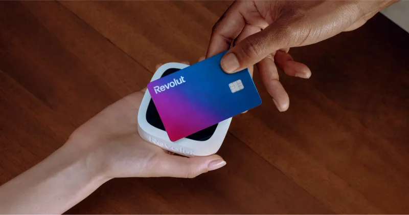 A Revolut card being held over a contactless payment reader.