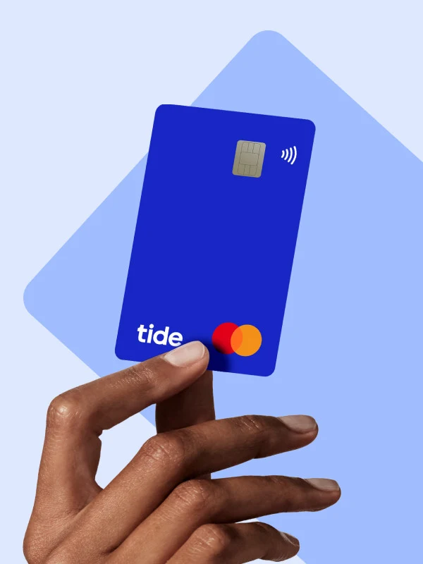 A hand holding a blue Tide business debit card.