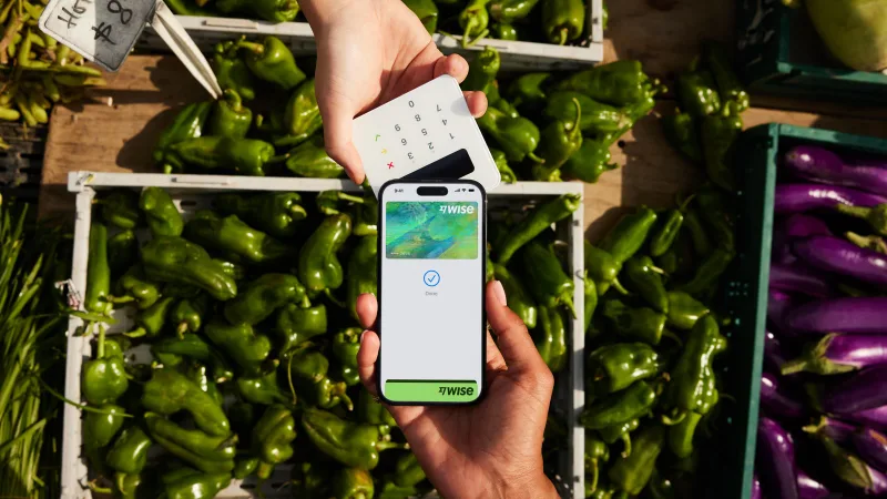 A digital Wise card on a phone being used at a market payment terminal.